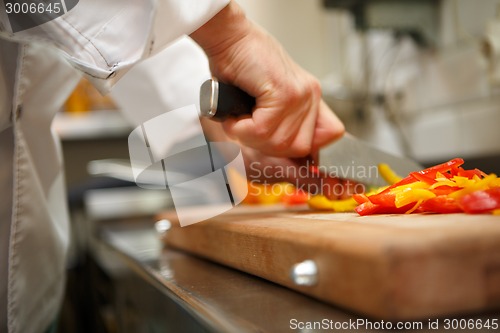 Image of closeup on hands cutting yellow pepper