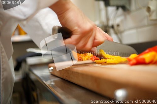 Image of closeup on hands cutting yellow pepper