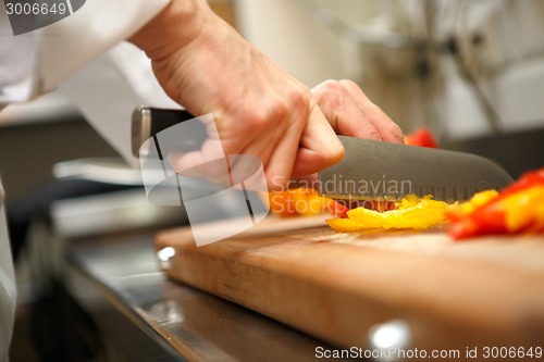 Image of closeup on hands cutting yellow pepper