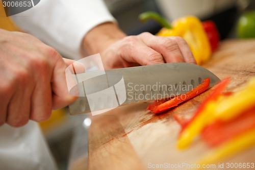 Image of closeup on hands cutting yellow pepper