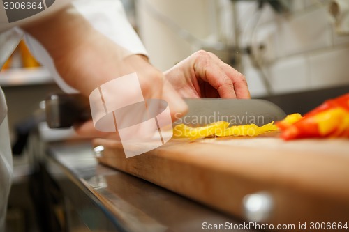 Image of closeup on hands cutting yellow pepper