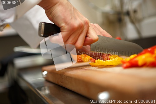 Image of closeup on hands cutting yellow pepper