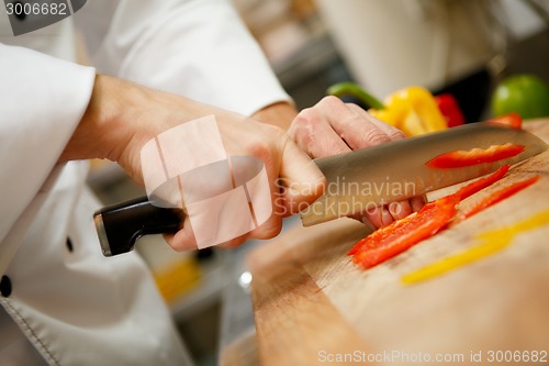 Image of closeup on hands cutting yellow pepper
