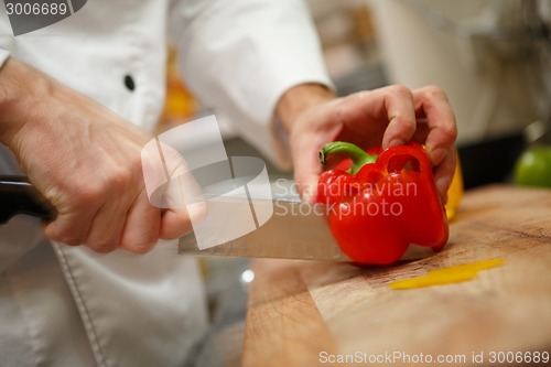 Image of closeup on hands cutting yellow pepper