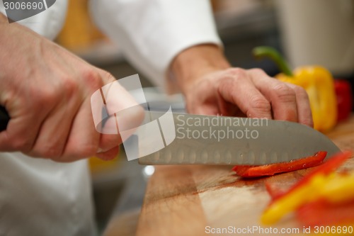 Image of closeup on hands cutting yellow pepper