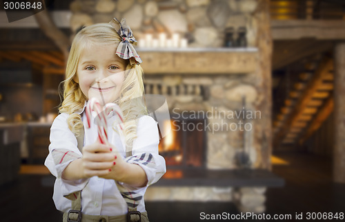 Image of Cute Young Girl Holding Candy Canes in Rustic Cabin