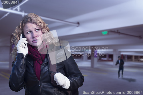 Image of Frightened Young Woman On Cell Phone in Parking Structure