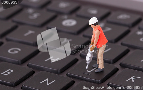 Image of Miniature worker with drill working on keyboard