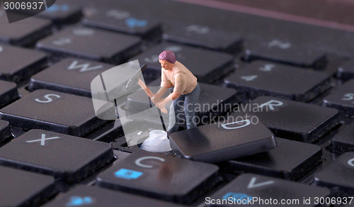 Image of Miniature worker with pickaxe working on keyboard