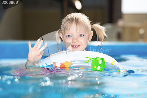 Image of Little blond girl swimming in water pool