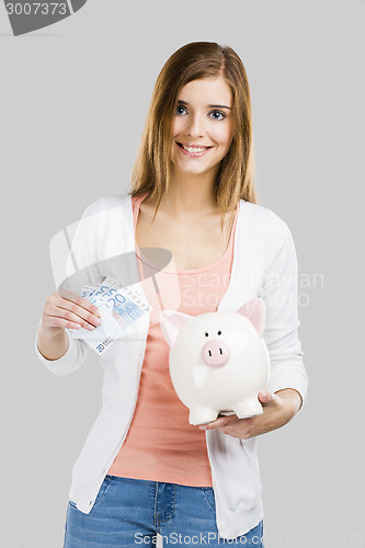 Image of Beautiful woman putting money in a piggy bank