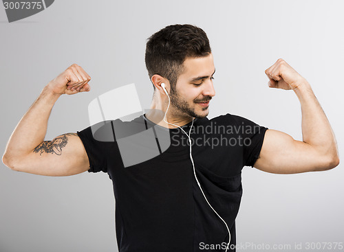 Image of Man listen  music and looking his muscles