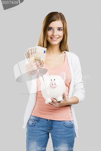 Image of Beautiful woman putting money in a piggy bank