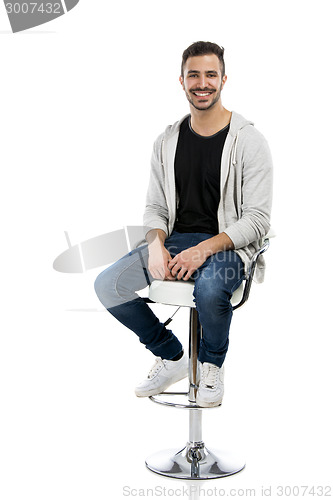 Image of Happy young man sitting on a bench