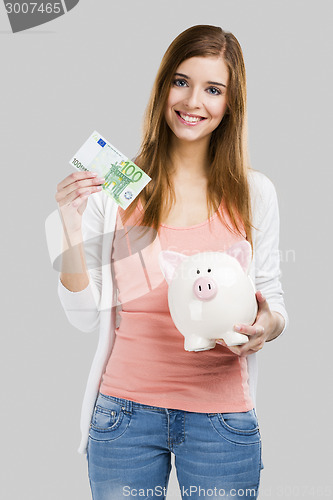 Image of Beautiful woman putting money in a piggy bank