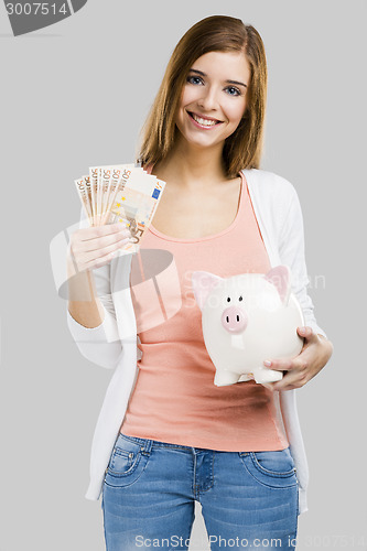 Image of Beautiful woman putting money in a piggy bank