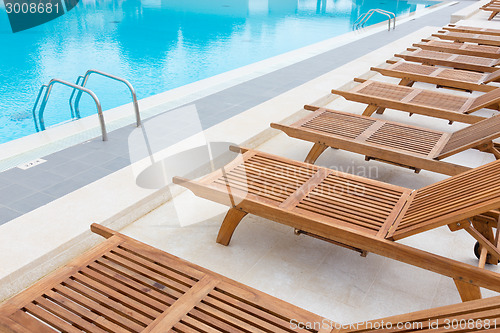 Image of Swimming pool with wooden sunbeds.