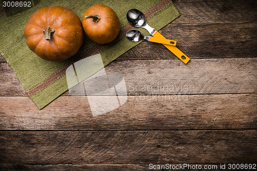 Image of Rustic style two pumpkins with spoons on green napkin and wood 