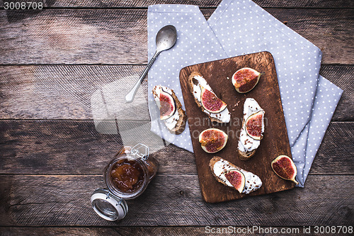 Image of Bruschetta, jam and Sliced figs on chopping board in rustic styl