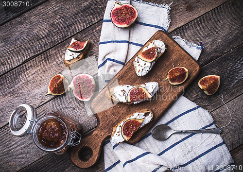 Image of Bruschetta snacks with cut figs on napkin in rustic style