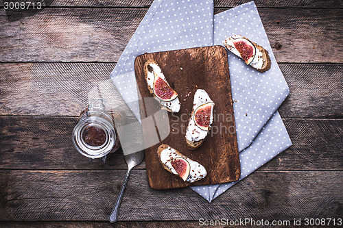Image of Bruschetta with cream cheese and figs on chopping board in rusti