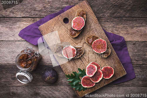 Image of Sliced figs and bread with jam on choppingboard in rustic style