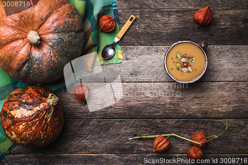 Image of Pumpkins and soup with seeds and ground cherry on wooden table