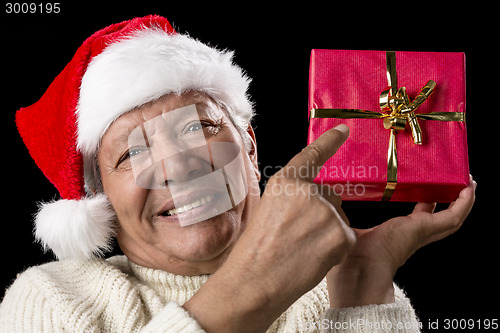 Image of Male Senior Pointing At Red Wrapped Christmas Gift