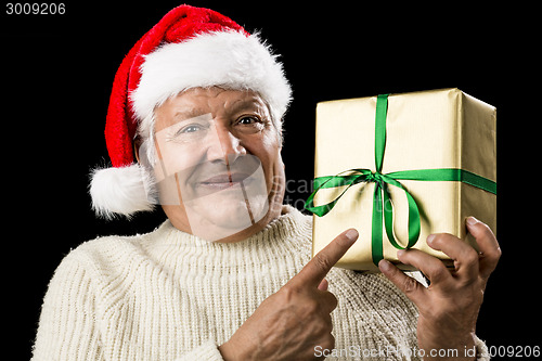 Image of Male Senior With Santa Cap Pointing At Golden Gift