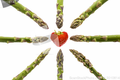 Image of Eight Asparagus Tips Pointing at One Strawberry