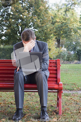 Image of Tired businessman with laptop