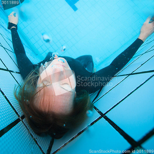 Image of Female diver with eyes closed underwater in swimming pool