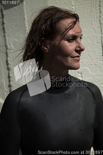 Image of Attractive female swimmer with wet hair wearing wetsuit