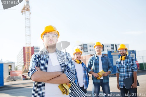 Image of group of smiling builders in hardhats outdoors