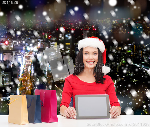 Image of smiling woman with shopping bags and tablet pc