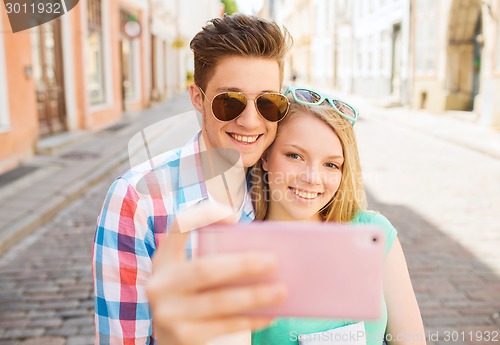 Image of smiling couple with smartphone in city