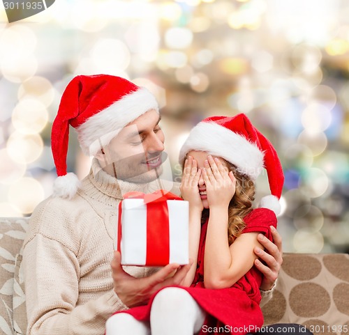 Image of smiling daughter waiting for present from father