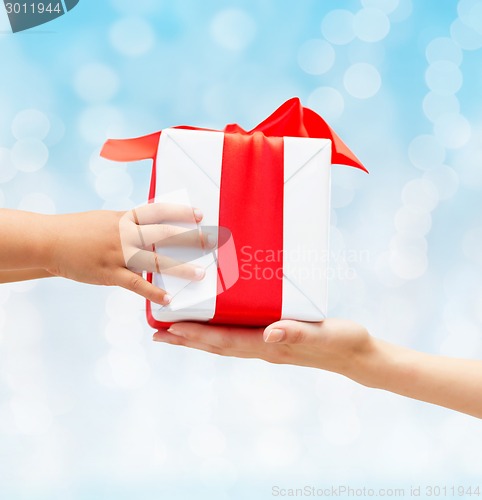 Image of close up of child and mother hands with gift box