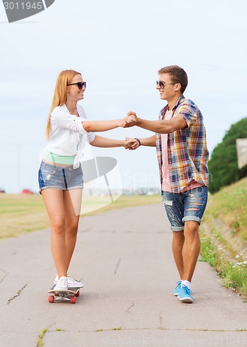 Image of smiling couple with skateboard outdoors