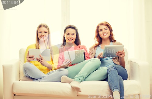 Image of three smiling teenage girls with tablet pc at home