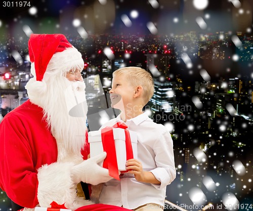 Image of smiling little boy with santa claus and gifts