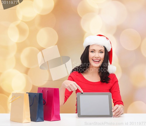 Image of smiling woman in santa hat with bags and tablet pc