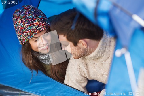 Image of smiling couple of tourists looking out from tent