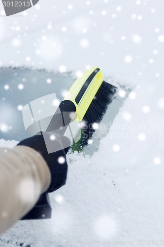 Image of closeup of man cleaning snow from car