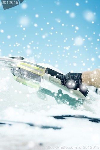 Image of closeup of man cleaning snow from car