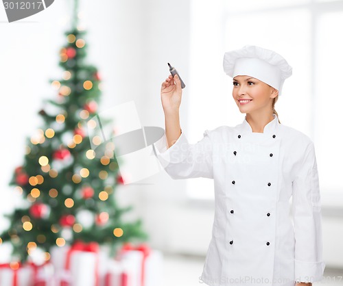 Image of smiling female chef writing something on air