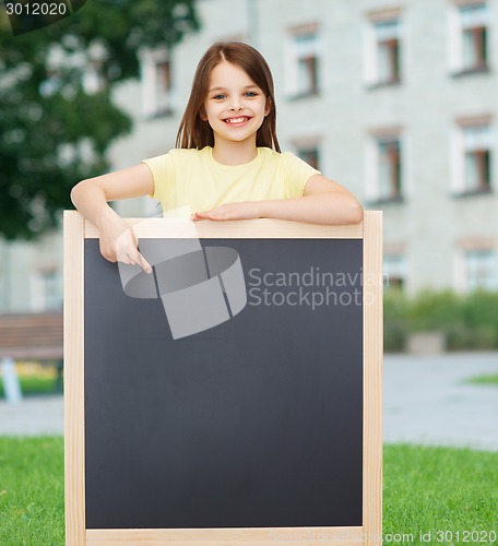 Image of happy little girl pointing finger to blackboard