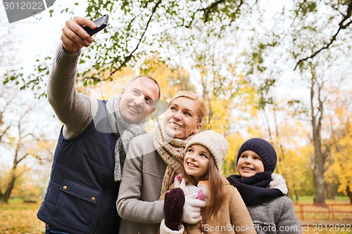 Image of happy family with camera in autumn park