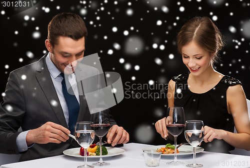 Image of smiling couple eating main course at restaurant