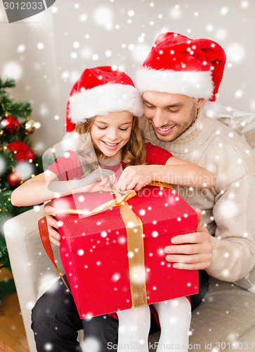 Image of smiling father and daughter with gift box at home